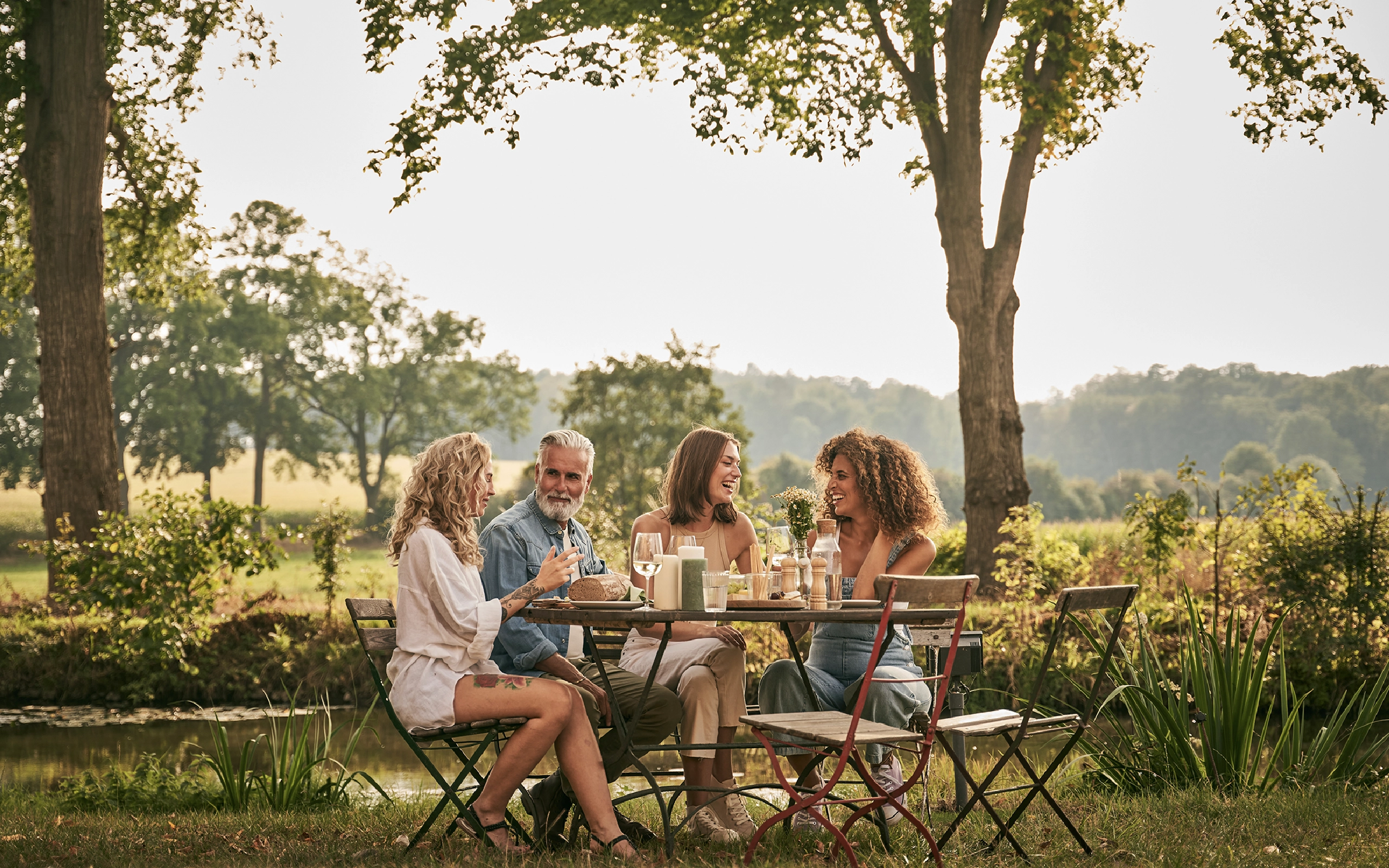 Herbalind Markenentwicklung mit natürlicher Lifestyle-Szene einer Gruppe am gedeckten Tisch im Grünen