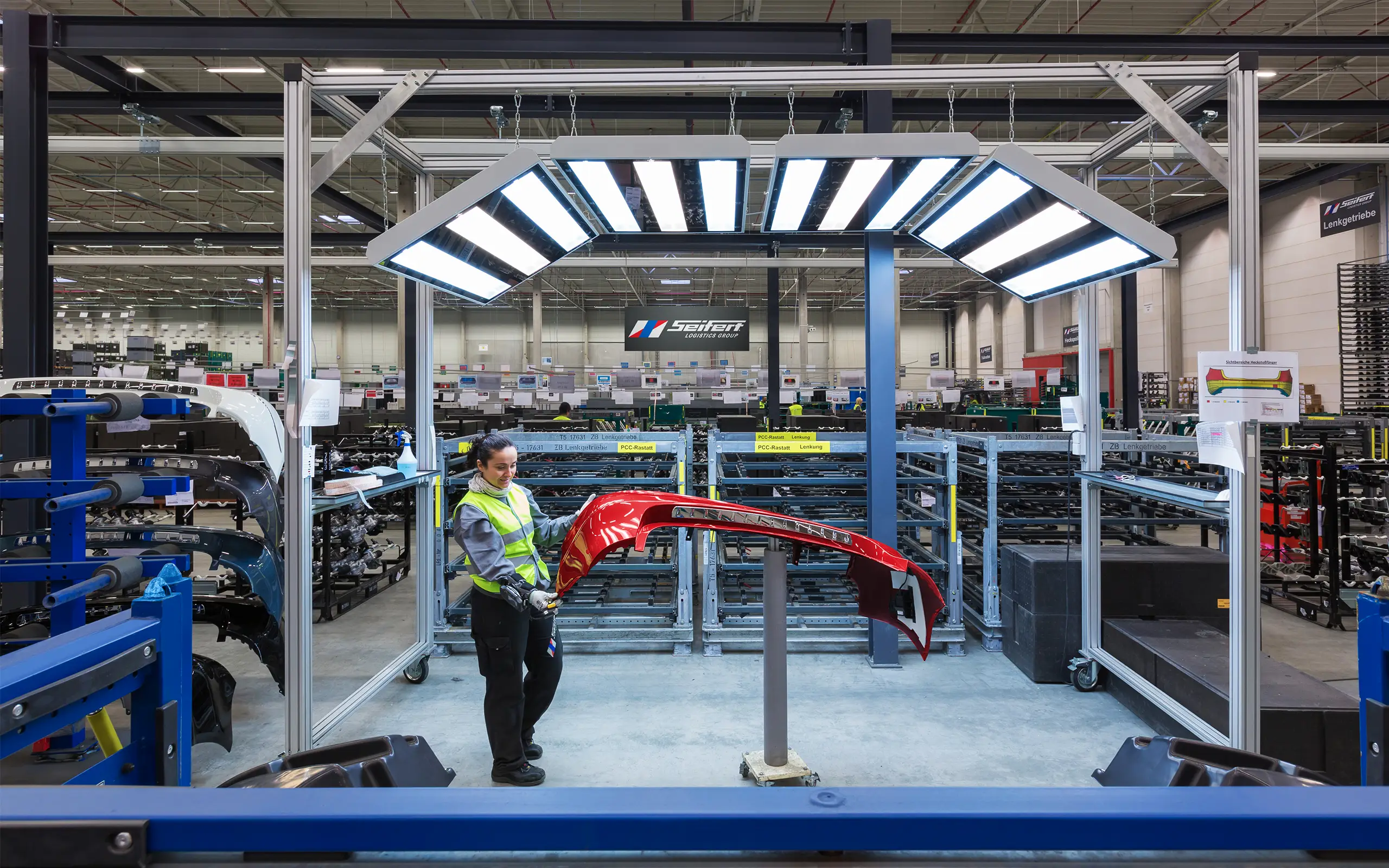 Seifert Logistics Mitarbeiterin in der Produktion mit Fahrzeugbauteil